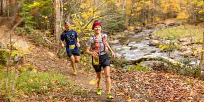 Défi des Couleurs Simard - Deux individus en train de courir dans une forêt automnale