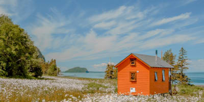 Tiny house orange au bord du fleuve au printemps. 