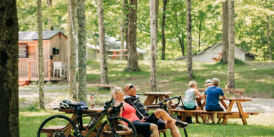 Érablière du Village - A man and a woman are seated at a picnic table, with their bikes leaning against it.