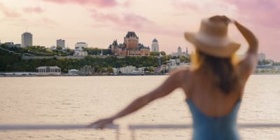 A woman is on the ferry, admiring the view of Château Frontenac