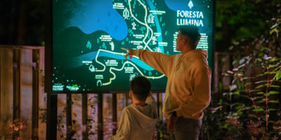 Foresta Lumina au Parc de la Gorge de Coaticook - Un homme et un garçon pointent sur une carte illuminée.