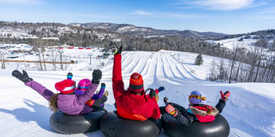 Famille aux glissades sur tube du Sommet Saint-Sauveur.