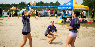 3 jeunes femmes jouant au volleyball.