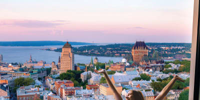 Une femme se réveillant dans un lit douillet avec une vue spectaculaire sur Québec.