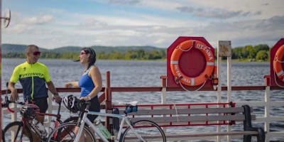 Une homme et une femme sont debout sur le bord de l'eau, avec leur vélo à leur côté