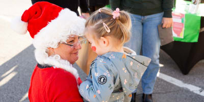 Marché de Noël de Prévost - Une femme déguisée en Mère Noël tient un enfant dans ses bras.