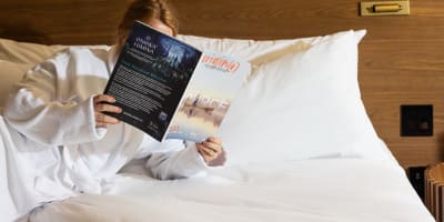 Femme dans une chambre d'hôtel lisant un livre.