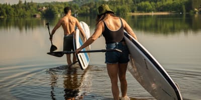 Deux personnes avec leur planche à pagaie au Parc régional Sainte-Agathe-des-Monts.