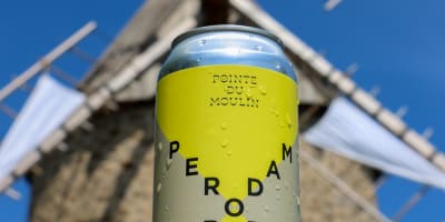 Perodam Microbrasserie Solidaire - Cannette de bière, un moulin en arrière-plan.
