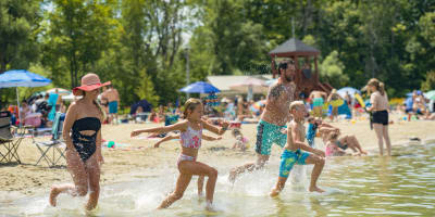 A family running through the water at the beach.