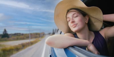 Route touristique Tour du lac Saint-Jean - Une femme est dans une voiture en mouvement, la vitre baissée et profite du vent