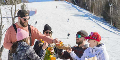 Des amis mangent au au bas de la montagne de ski du Sommet Saint-Sauveur.