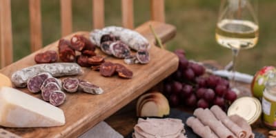Plateau de charcuteries et vin blanc sur une table extérieur. 