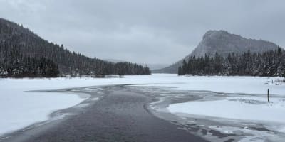Paysage hivernale avec rivière et montagnes.