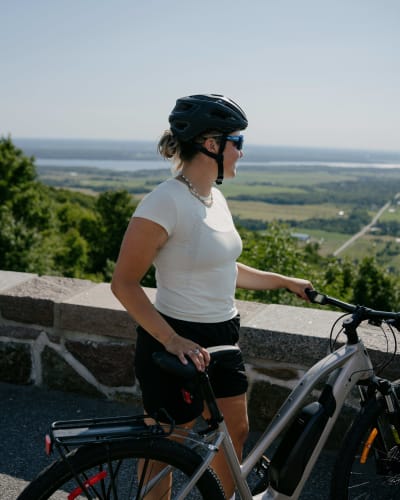 A woman on a bicycle at the Champlain lookout point in the summer.