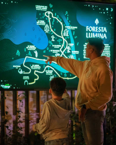 Foresta Lumina au Parc de la Gorge de Coaticook - Un homme et un garçon pointent sur une carte illuminée.