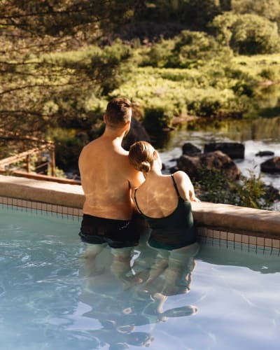 Un couple se détend dans une piscine extérieur en pleine nature.