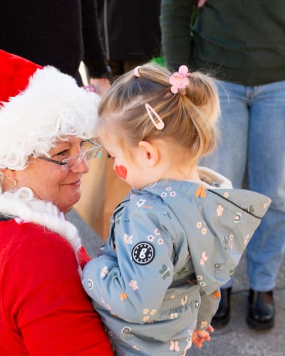 Marché de Noël de Prévost - Une femme déguisée en Mère Noël tient un enfant dans ses bras.