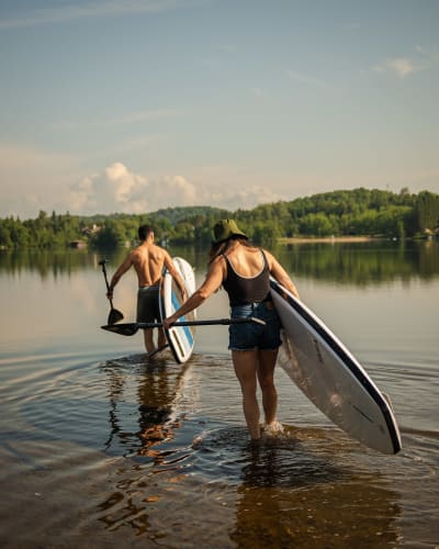 Deux personnes avec leur planche à pagaie au Parc régional Sainte-Agathe-des-Monts.