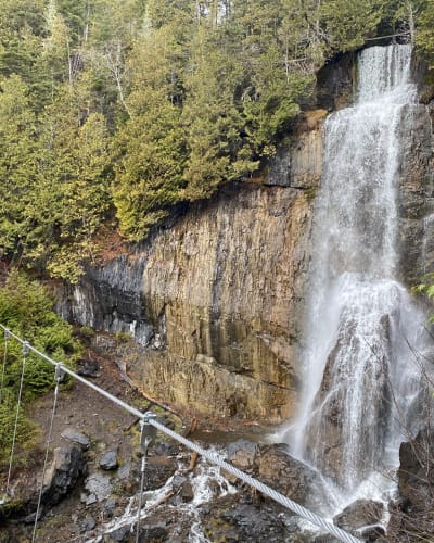 Pont flottant devant des chutes: Parcours Aventures - Via ferrata Gaspésie.