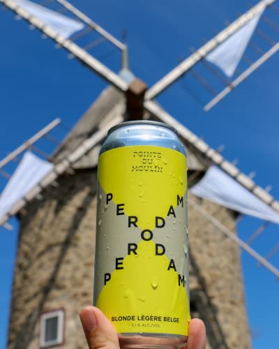Perodam Microbrasserie Solidaire - Cannette de bière, un moulin en arrière-plan.