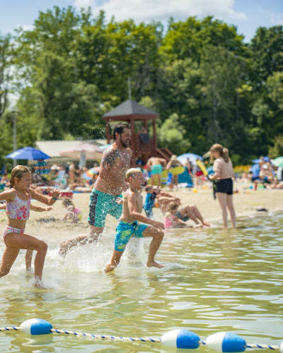 A family running through the water at the beach.