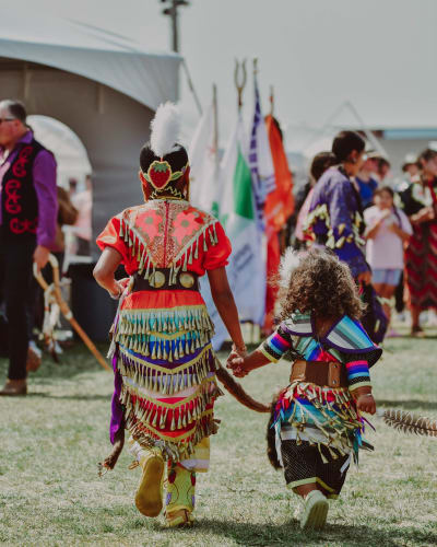 Two young Native girls adorned in their regalia at the powwow.