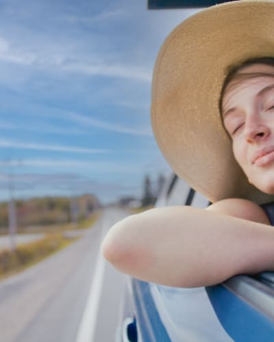 Route touristique Tour du lac Saint-Jean - Une femme est dans une voiture en mouvement, la vitre baissée et profite du vent