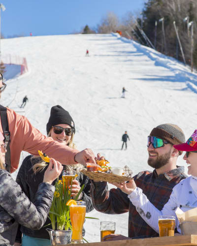 Des amis mangent au au bas de la montagne de ski du Sommet Saint-Sauveur.