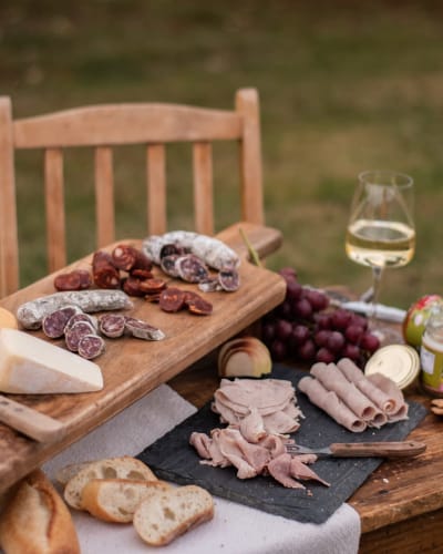 Plateau de charcuteries et vin blanc sur une table extérieur. 