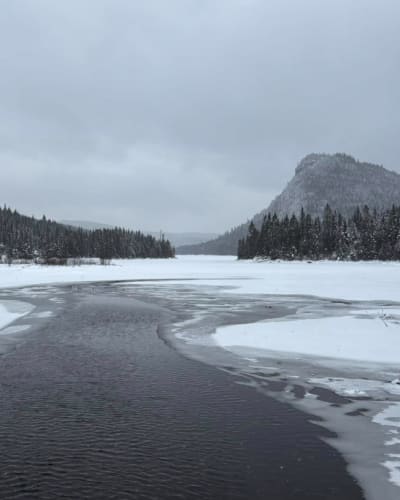 Paysage hivernale avec rivière et montagnes.