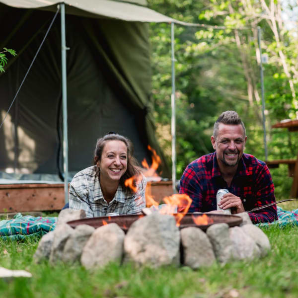 Couple in front of a ready-to-camp tent at Camping Sainte-Agathe-des-Monts in Sainte-Agathe-des-Monts Regional Park.
