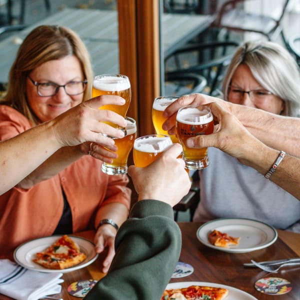 Des gens autour d'une table avec une pizza et de la bière de Des Cantons Microbrasserie.