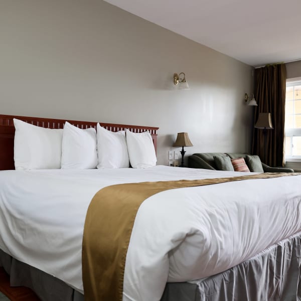 Room with king bed and sofa at Hotel & Suites Les Laurentides.