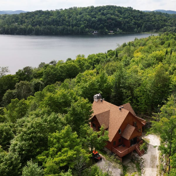 Vue aérienne d'un chalet près d'un lac en été.