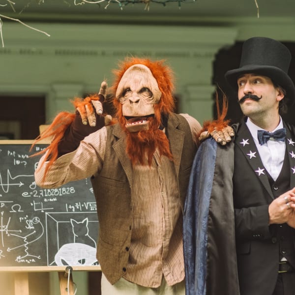 La Grande Échappée - A person dressed as a magician accompanied by a person dressed as a monkey.