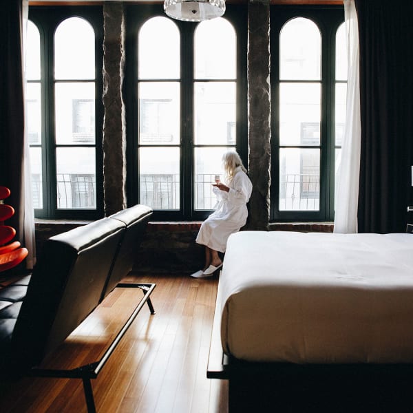 Le Petit Hôtel - Une personne en peignoir est assise sur le bord des fenêtres dans une chambre
