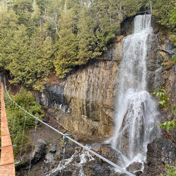 Pont flottant devant des chutes: Parcours Aventures - Via ferrata Gaspésie.