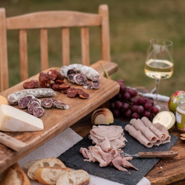 Plateau de charcuteries et vin blanc sur une table extérieur. 