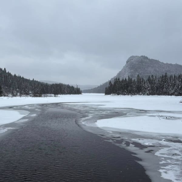 Paysage hivernale avec rivière et montagnes.