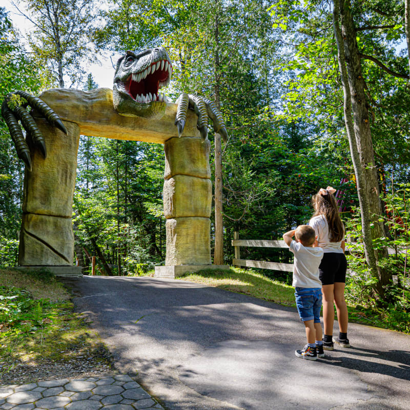 Deux enfants devant une porte surmontée d'une tête de dinosaure