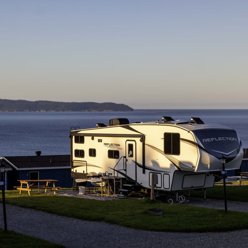 Roulotte installée sur un terrain de camping avec vue sur l'eau.