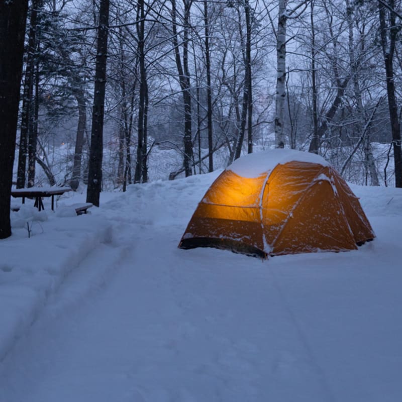 Tente de camping éclairé sur la neige