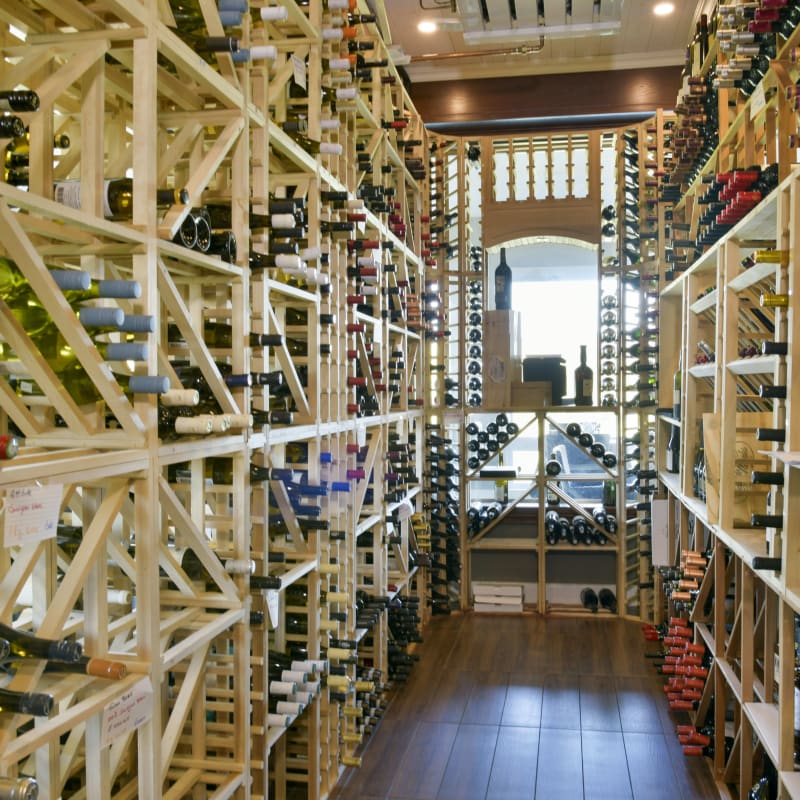 Intérieur d'un cellier bien éclairé avec de nombreuses bouteilles de vin.
