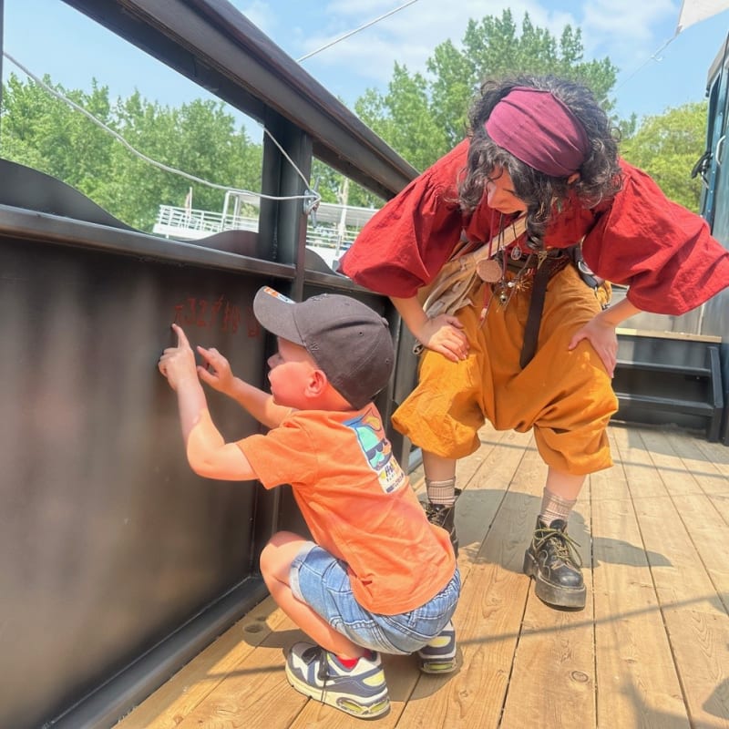 Enfant et animatrice en costume sur un bateau pirate.