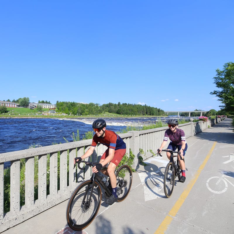 Deux cyclistes sur une piste cyclable au bord de l'eau.