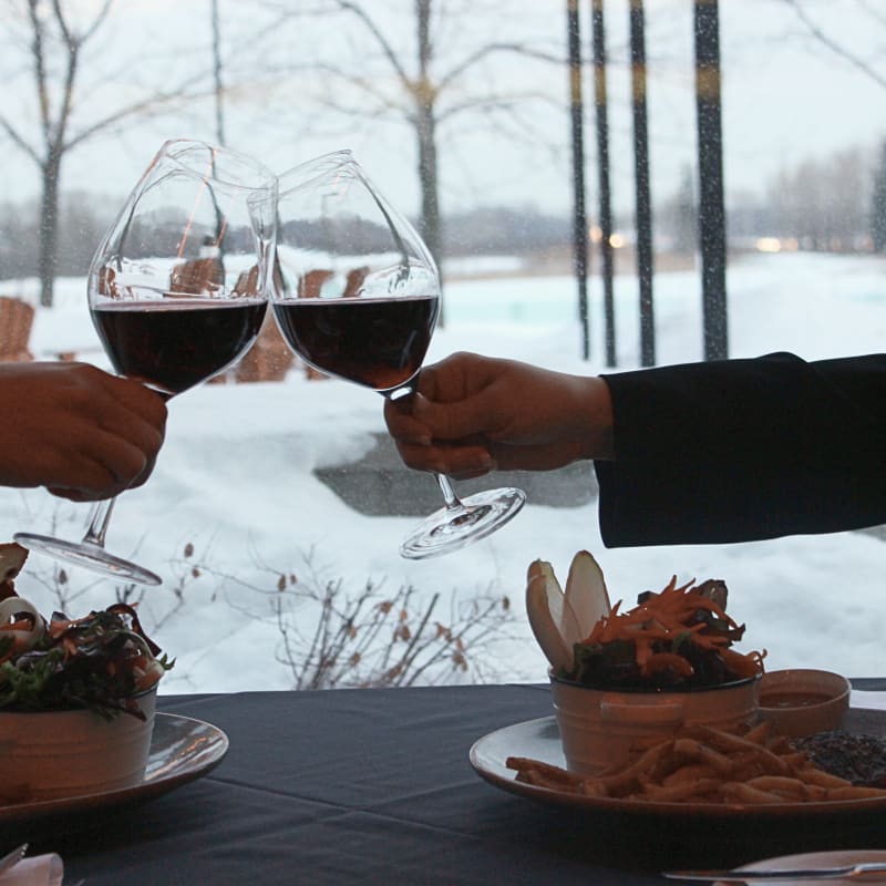 Deux personnes qui trinquent devant la fenêtre d'un resto en hiver.
