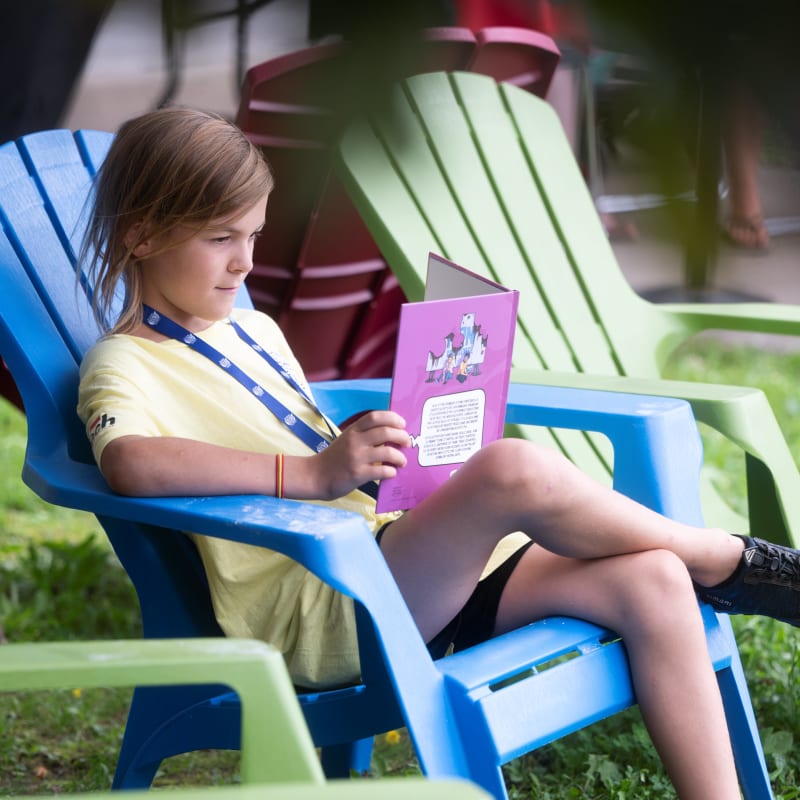 A boy sitting on a chair reading a comic book