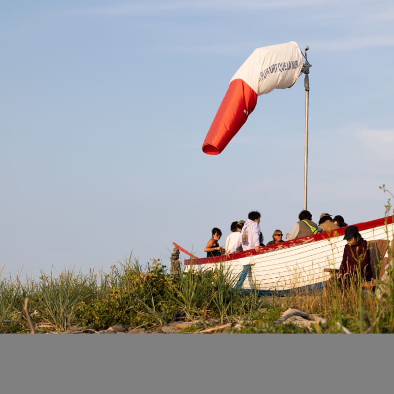 Groupe dans un bateau aménagé comme terrasse sur la rive au Festival en chanson de Petite-Vallée.