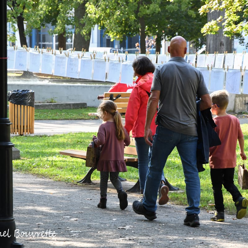 Family walking on a trail next to a rope of poems in Trois-Rivières.